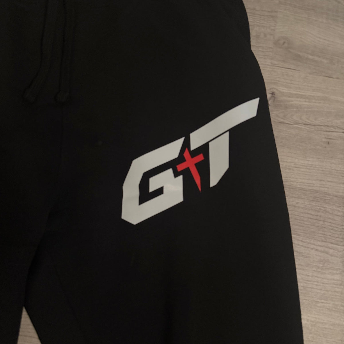 White and red GT mark on the black sweatpants