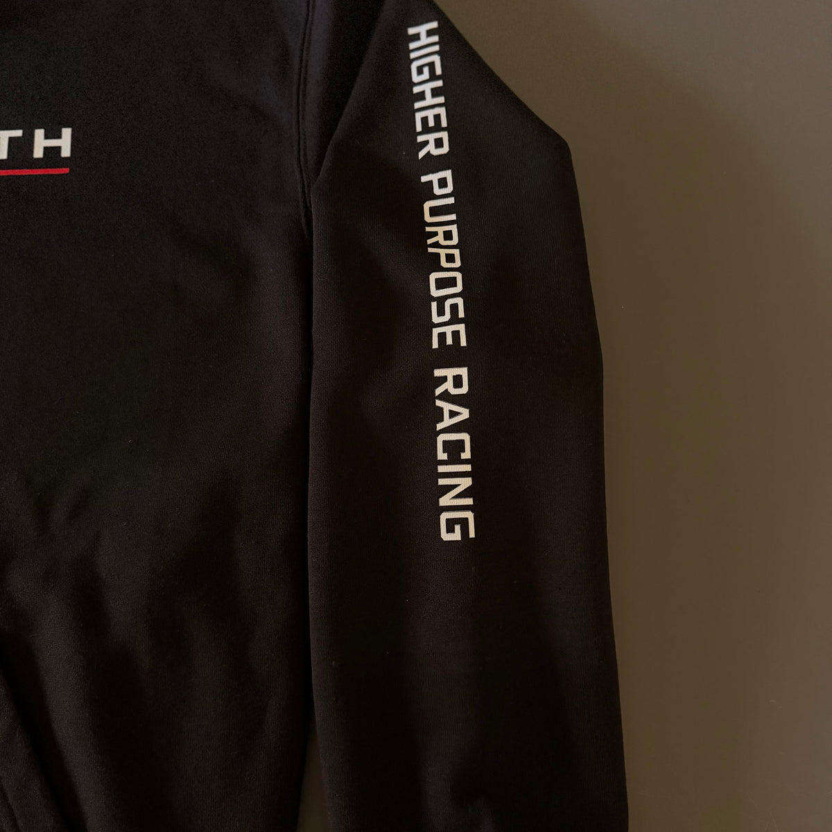 Higher Purpose Racing printed down the sleeve of the black hoodie