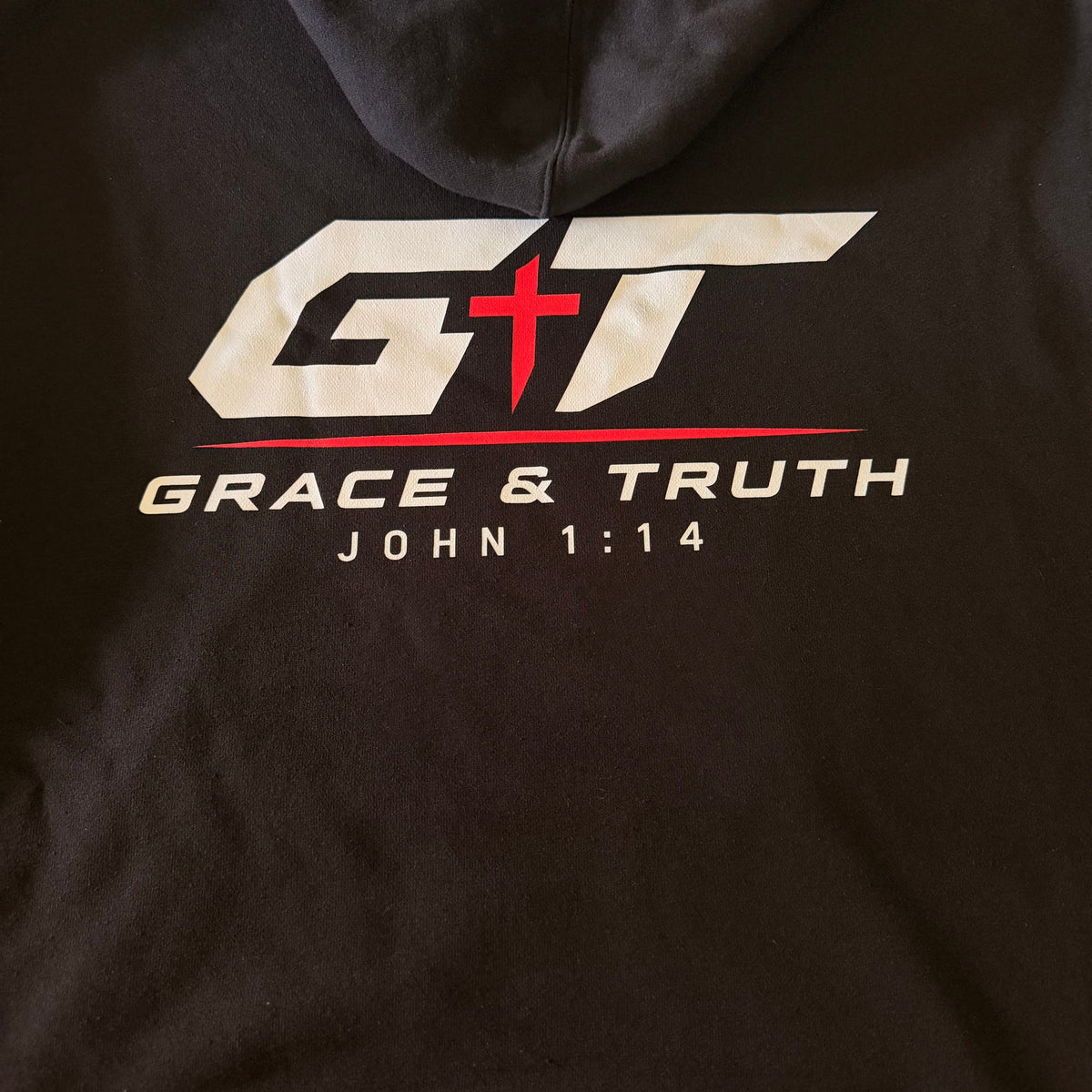 Close-up of the GT Grace & Truth John 1:14 back print on the black hoodie