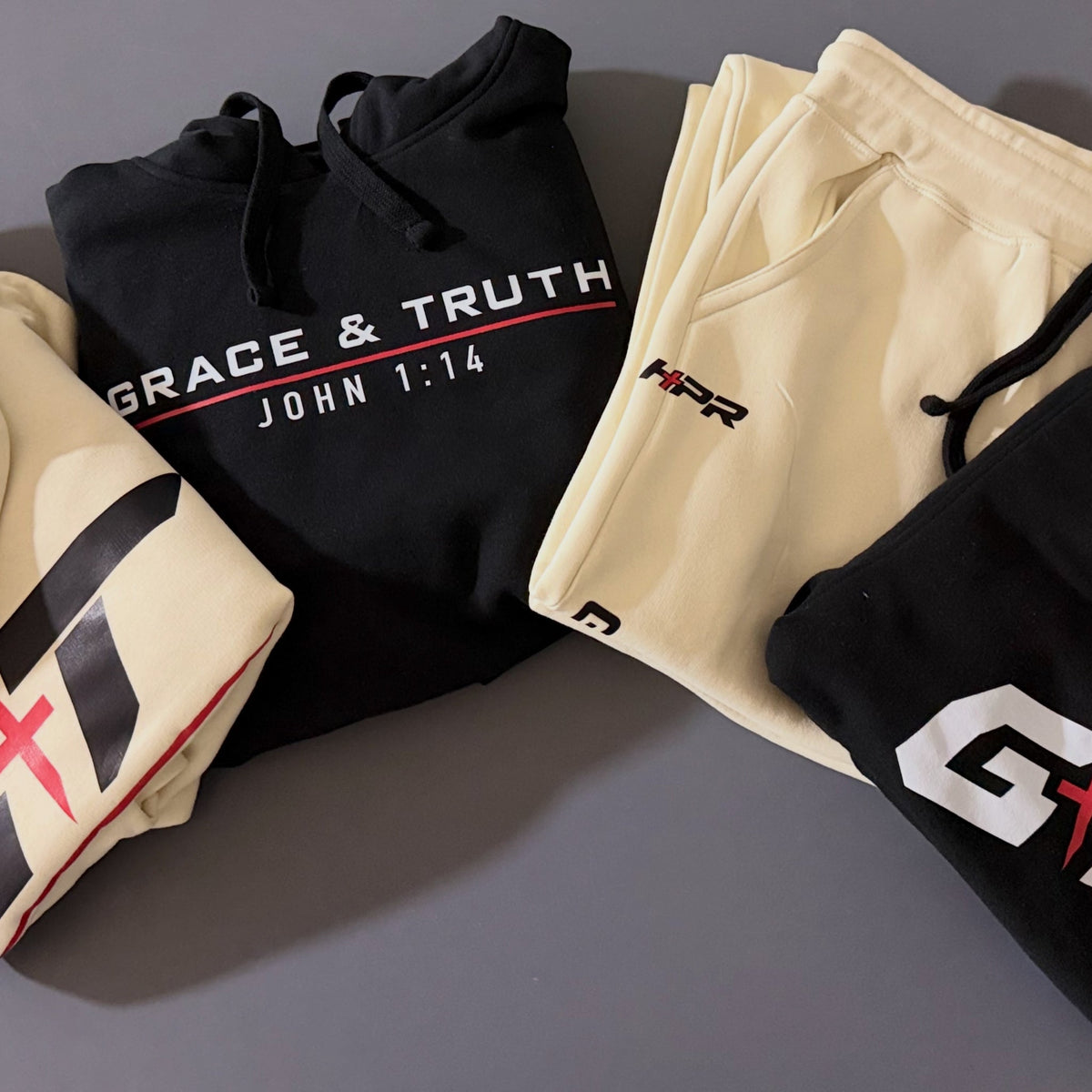 Black and Vintage Pearl Team Grace & Truth hoodies and sweatpants laid out together