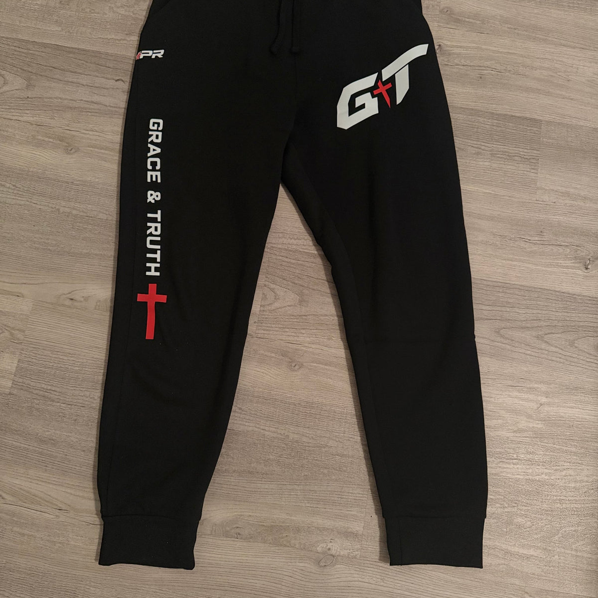 Black Team Grace & Truth sweatpants laid flat with white GT mark and Grace & Truth leg print