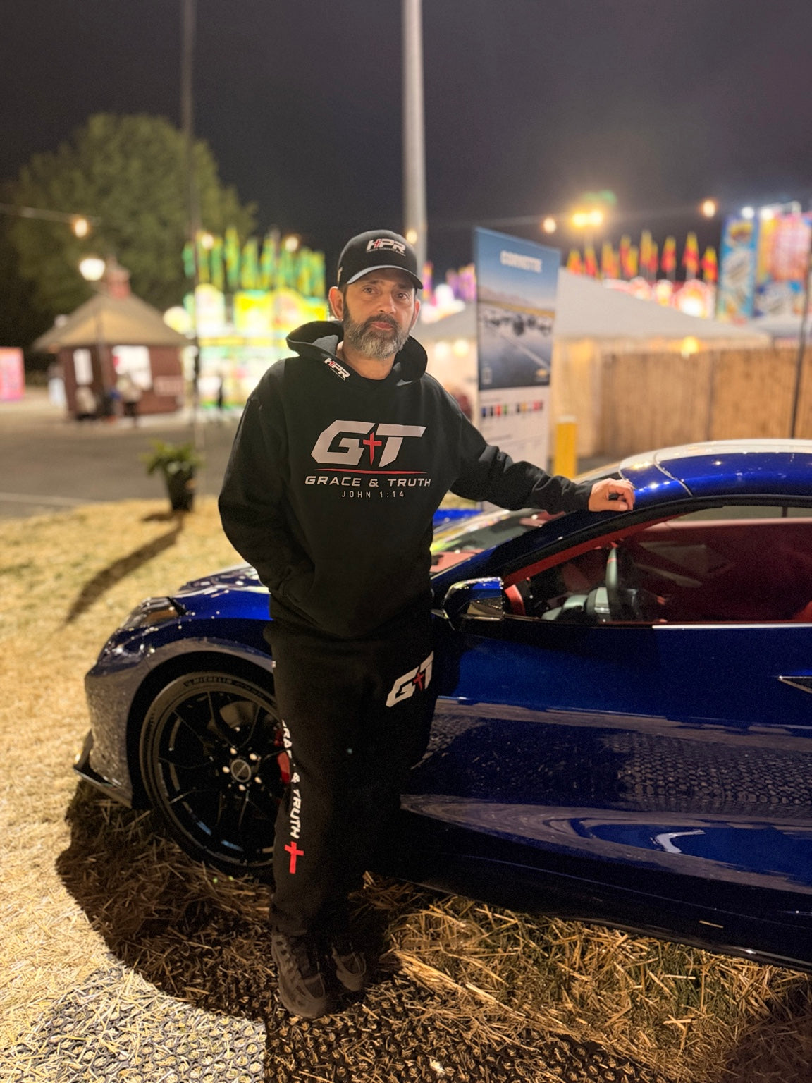 Grace & Truth black sweatsuit worn beside a race car